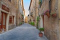 Pienza, Italy Ã¢â¬â May 27, 2017: Beautiful narrow street with sunlight and flowers in the village of Pienza, Italy Royalty Free Stock Photo